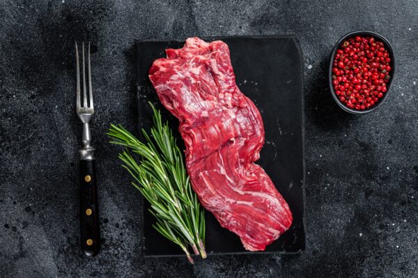 Raw machete skirt beef meat steak on marble board. Black background. Top view